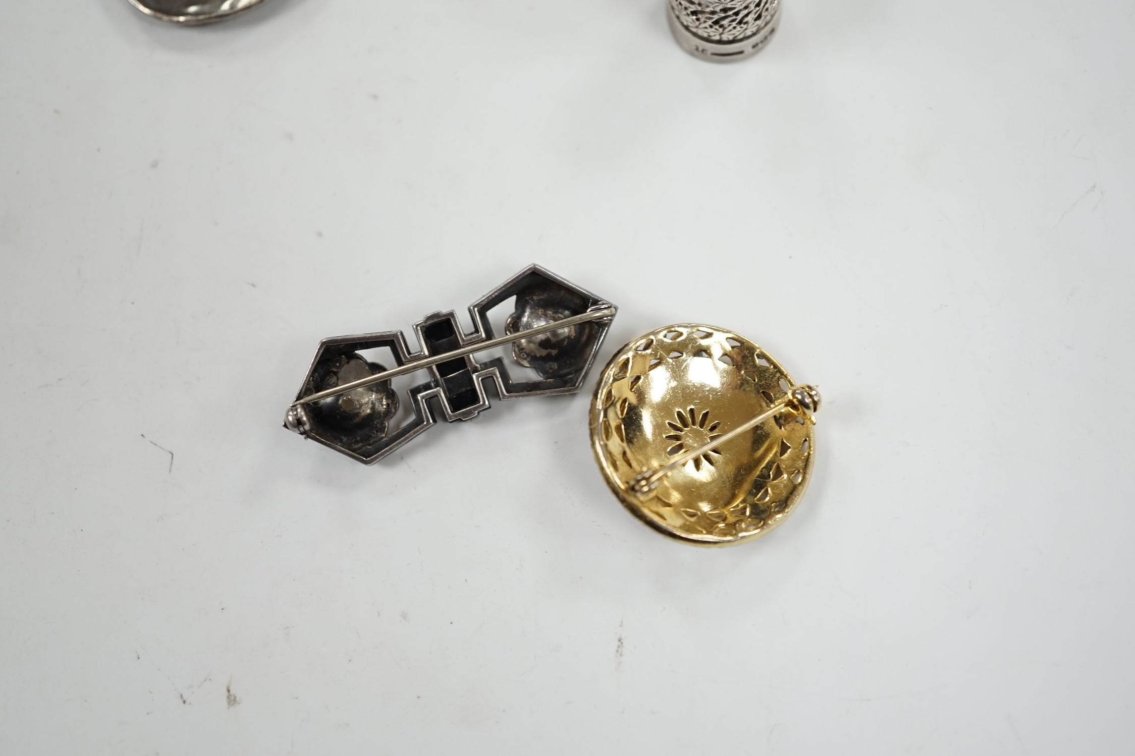 A George V silver thimble, a later silver brooch, a white metal, marcasite and black onyx brooch and one other brooch.